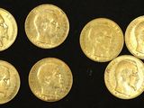 six gold sovereigns of different sizes and shapes on a black surface