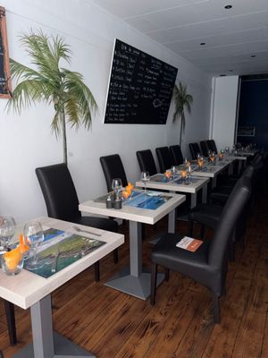 Ce restaurant compte de nombreuses tables et chaises, et les menus sont affichés au mur.
