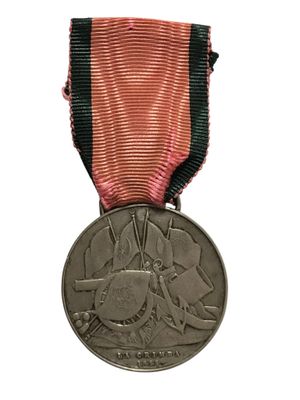 une ancienne médaille avec un ruban rouge sur fond blanc