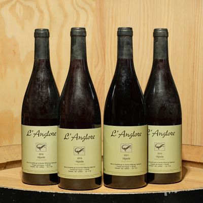 four bottles of wine are lined up on a wooden barrel