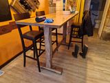 une table en bois avec deux chaises et un tableau noir accroché au mur