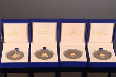 four gold coins are in a blue box on a table