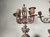 pair of antique bronze candelabs on stand against a white wall