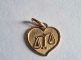 un pendentif en or en forme de cœur orné de balances
