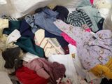 a pile of clothes that is sitting on a bed
