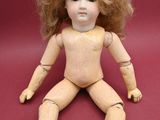 a wooden doll sitting on the floor with a red background