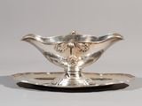 une assiette en argent ornée d'une fleur sur un fond blanc