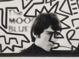 black and white photograph of a man in front of a wall with graffiti