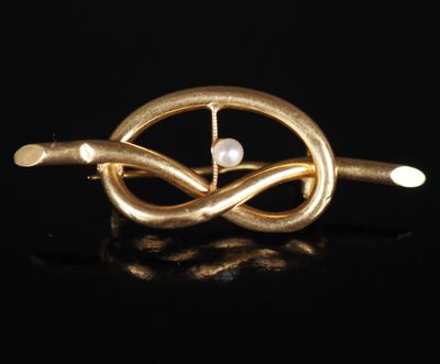une broche en or ornée d'une perle au centre