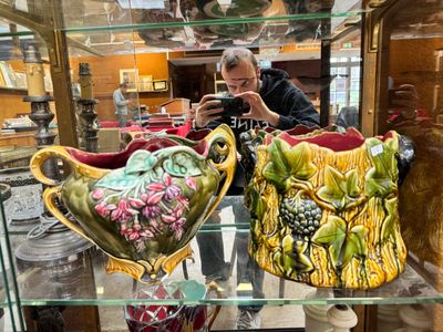 a man taking a picture of two vases in a glass case