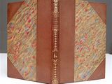 a brown book with gold trim on a white table