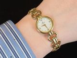 a woman wearing a gold watch on her wrist
