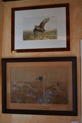 two framed pictures on the wall above a sink