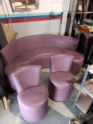 a purple curved couch and two stools in a room