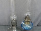 une paire de lampes à huile anciennes, dotées d'abat-jours en verre bleu, posées sur une table