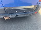 a close up of a blue car with a rusted bumper