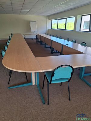 tables and chairs in a large conference room with a projector screen in the background