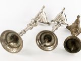 three antique silver bells on a white surface with a white background