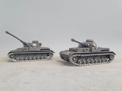 two toy tanks sitting side by side on a white surface