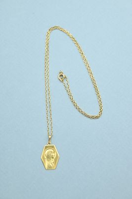 a gold necklace with a small coin on a chain