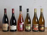 several bottles of wine are lined up on a wooden table