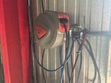 une photo d'un garage avec une porte rouge et un tuyau d'arrosage fixé sur le côté de la porte