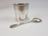 a silver cup with a spoon next to it