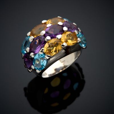 a close up of a ring with multi colored stones on a black surface