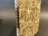 the book is sitting on a table next to a vase