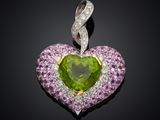 a close up of a green heart shaped pendant with pink and white diamonds