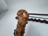 a wooden sculpture of a lion holding a pair of tongs