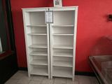 a tall white bookcase in the corner of the room
