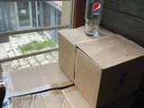 cardboard box on a window sill with a pepsi glass on top