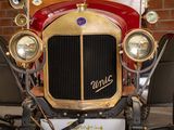 a red and gold vintage car parked in front of a brick wall