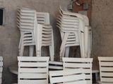 many white plastic chairs and a table in a room