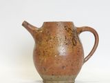 a small brown pitcher sitting on a white surface