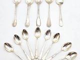 six cuillères en argent sont disposées en cercle sur une surface blanche