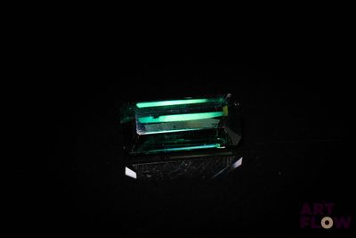 Une tourmaline vert émeraude brille dans l'obscurité