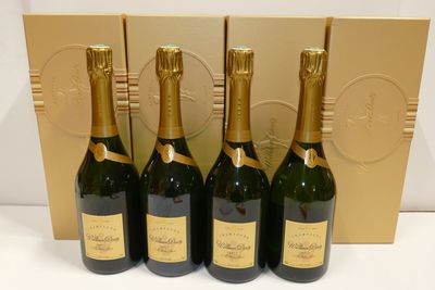 four bottles of champagne are lined up in front of a gold box