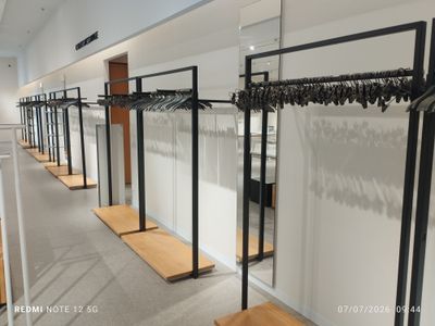 row of clothes racks in a clothing store with clothes hanging on them