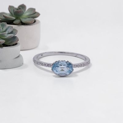 un gros plan d'une bague ornée d'une topaze bleue entourée de petites plantes