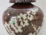 a brown and white vase sitting on a white surface