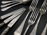 a lot of silverware on a table with a black background