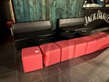 un banc rouge avec quatre tabourets devant un bar