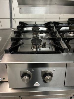 une plaque de cuisson en acier inoxydable dans une cuisine, sur laquelle sont posées des casseroles et des poêles