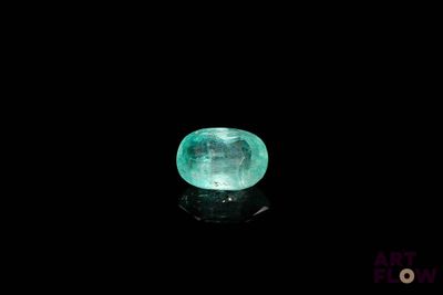 a close up of a green emerald stone on a black surface