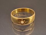 a gold ring with a pearl in it on a table