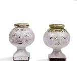 two white vases with faces on them on a white surface