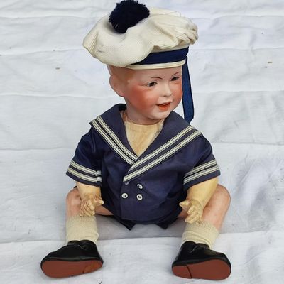une petite poupée de marin assise sur un drap blanc