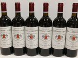 six bouteilles de vin rouge sont alignées sur une surface blanche